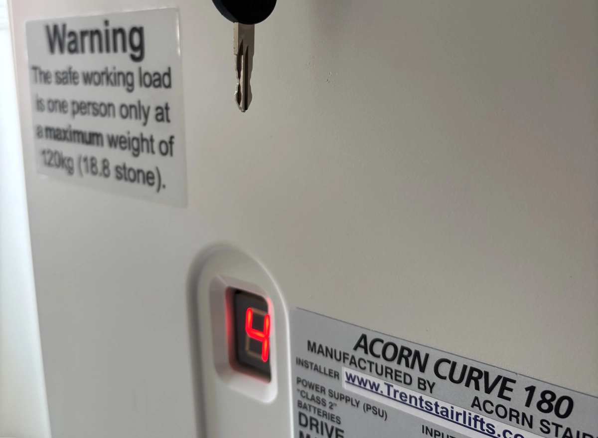 Red digital display and Acorn Curve 180 label on a stairlift carriage